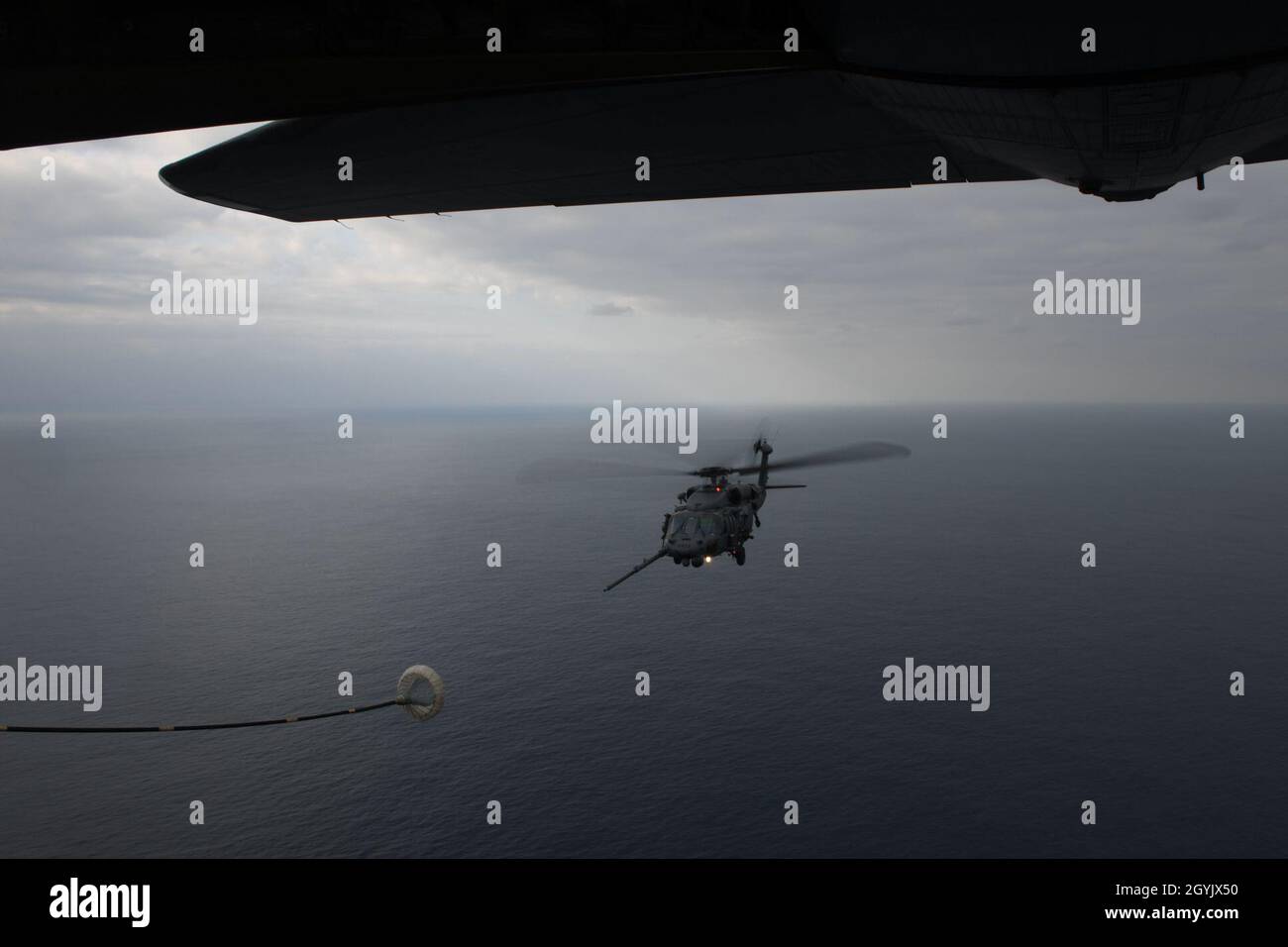 An HH-60G Pave Hawk assigned to the 33rd Rescue Squadron flies in to perform helicopter air-to-air refueling with an MC-130J Commando II from the 17th Special Operations Squadron above the Pacific Ocean during Exercise Westpac Rumrunner Jan. 10, 2020. WestPac  Rumrunner provides 18th Wing assets opportunities to hone critical expeditionary skillsets with joint partners across the Indo-Pacific. (U.S. Air Force photo by Staff Sgt. Benjamin Sutton) Stock Photo