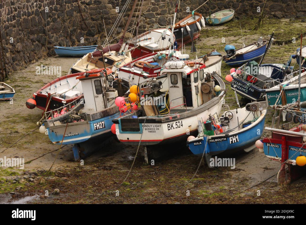 Small fishing boats tied up and dried out in tidal harbour, Cornwall, England Stock Photo