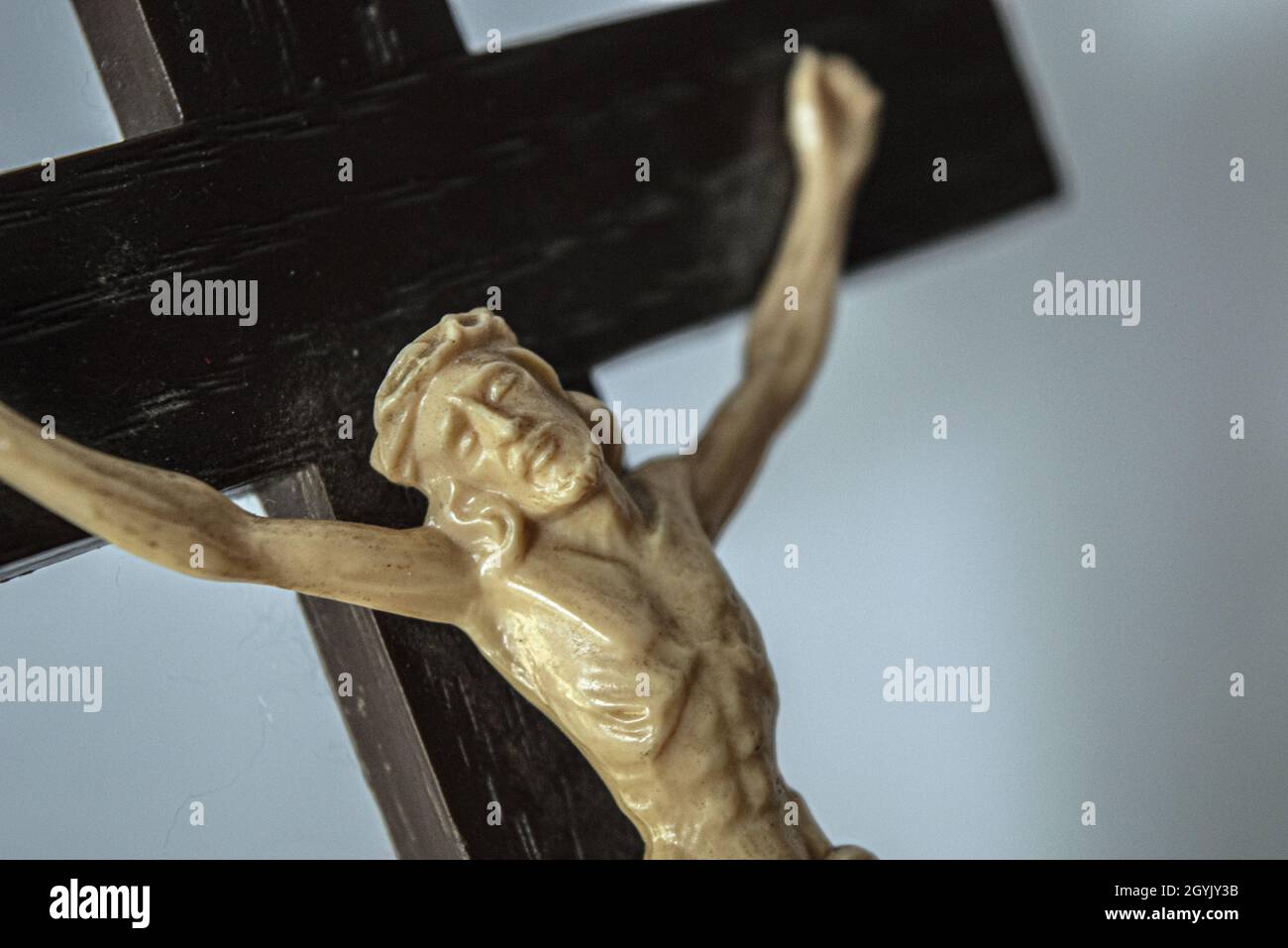 Closeup of a crucified Jesus statue on a wooden cross on a white ...
