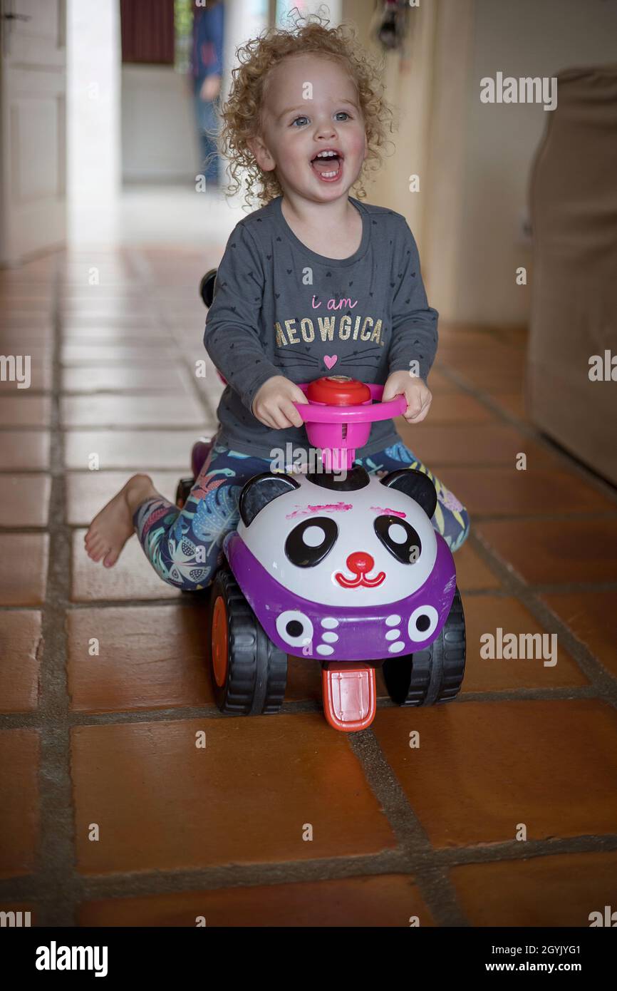 Young curly haired girl having great fun on ride on toy Stock Photo