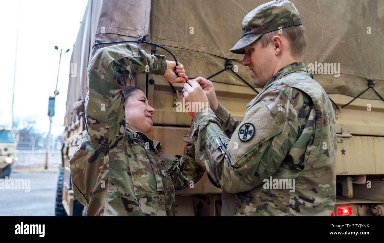 Staff Sgt. Ann Langenfeld (left) and Staff Sgt. Craig Gardener, both attached to the 812th Engineer Company (Sapper), work to repair the canopy strap of Light Medium Tactical Vehicle (LMTV)  in preparation for convoy operations in Lorain, Ohio, Jan. 11, 2020. The ability of units like the 812th to effectively maintain a constant state of readiness is fundamental to Ohio National Guard and its ability to be always ready, always there for its communities, state and nation. Stock Photo