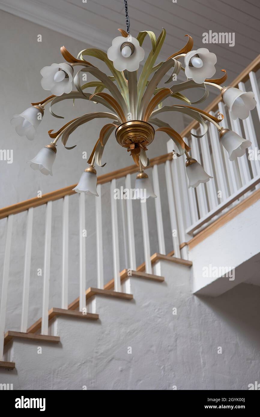 Beautiful floral light chandelier above a wooden stair case railing Stock Photo