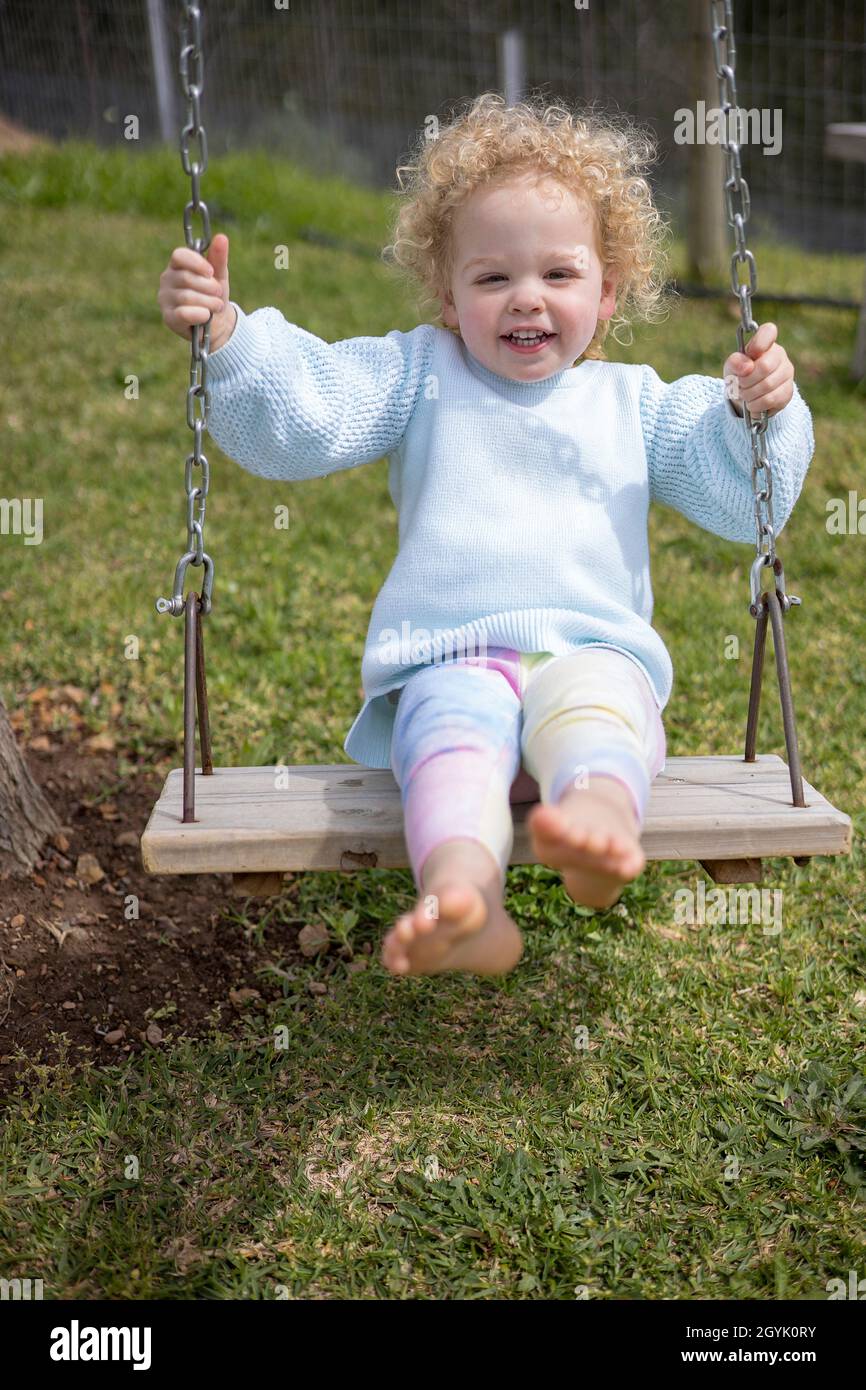 Curly haired young girl having fun on a swing Stock Photo