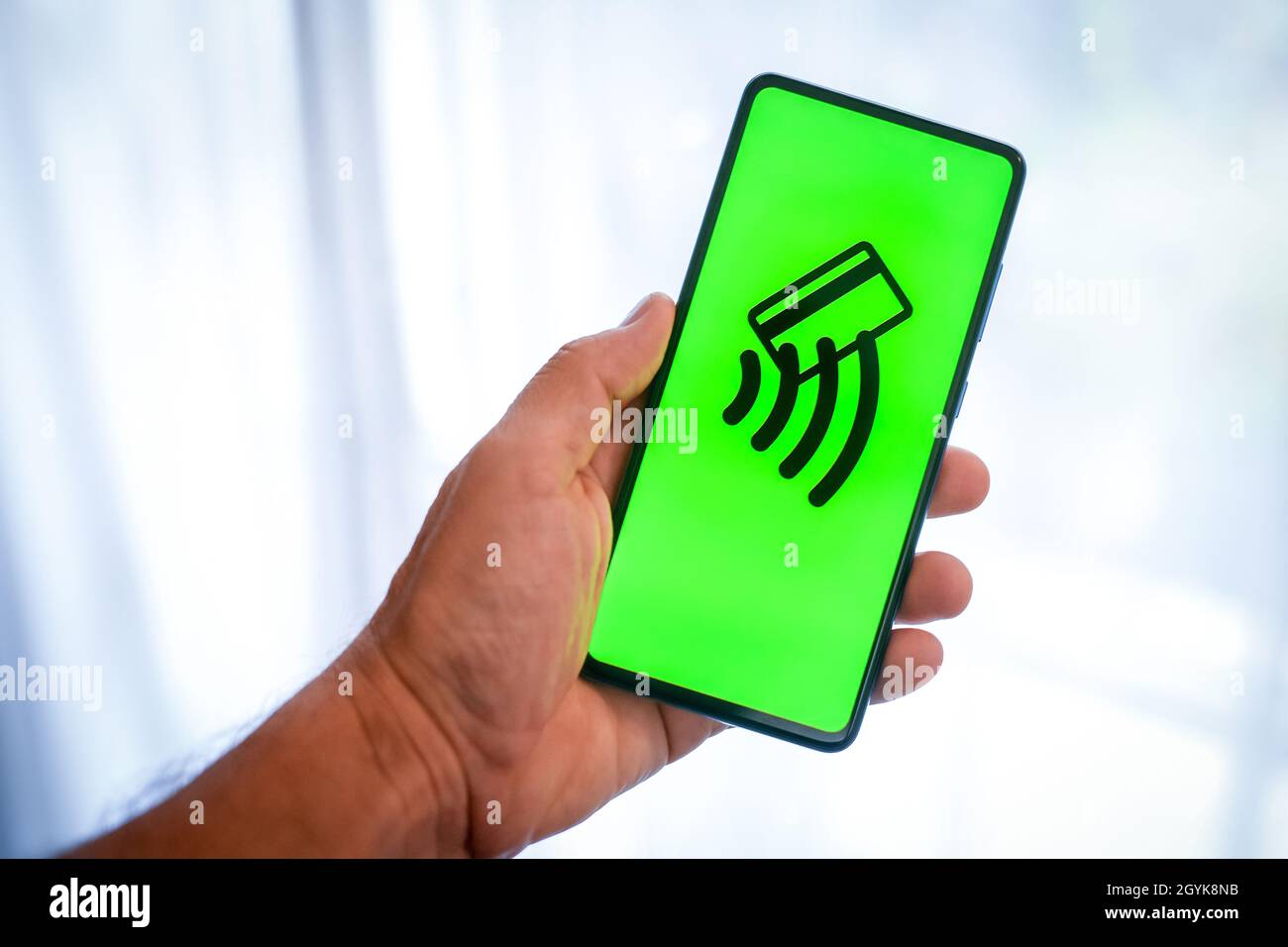 Close up view of hand with smartphone and contactless payment logo on display. Window on background. New technology, crypto value, wireless pay, conce Stock Photo