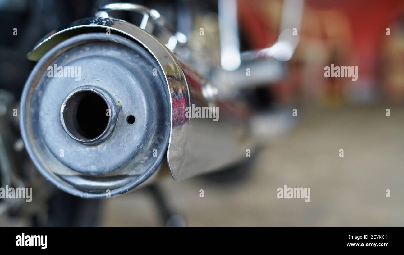 Motorcycle silencer end cap photo with blurred workshop background. Two wheeler spare parts photos. Stock Photo