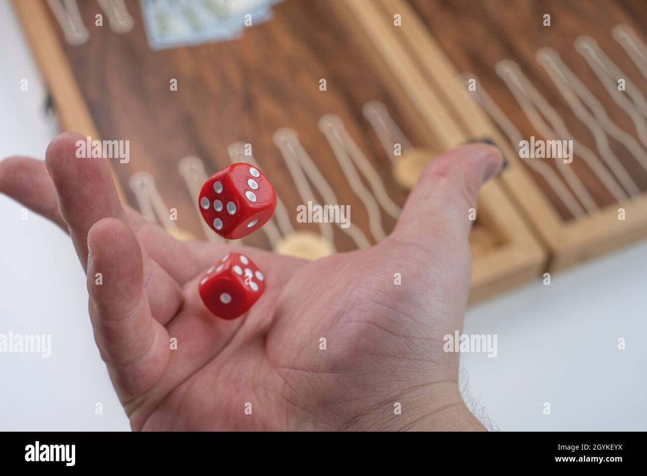 Throwing red dice in the air. Hand throw of the dice, background board game (backgammon Stock
