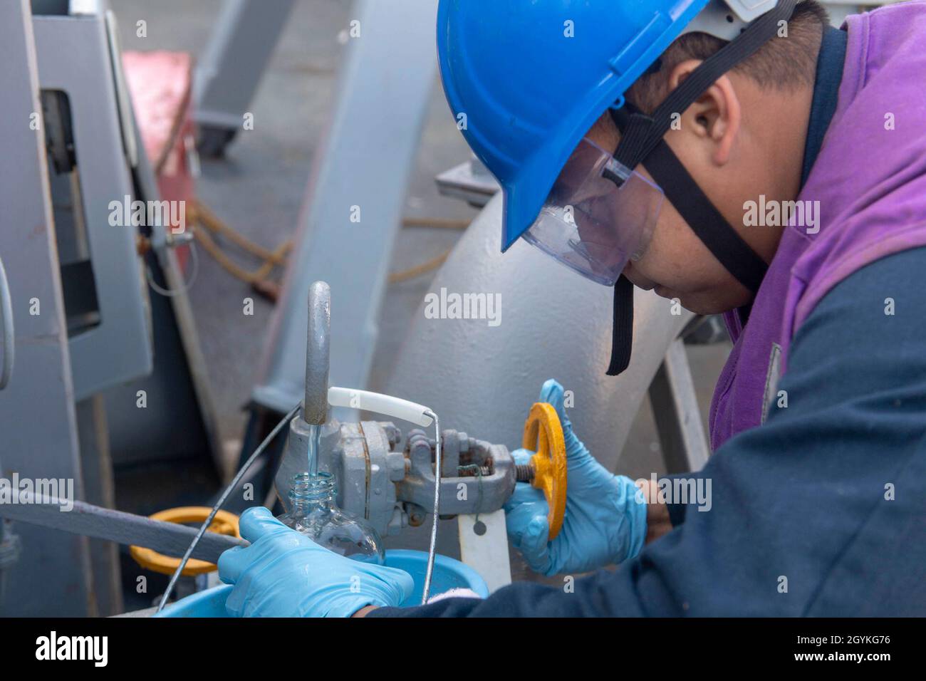 PACIFIC OCEAN (Jan. 18, 2020) Gas Turbine Systems Technician (Mechanical) 2nd Class Epifanio Macayan, from Buena Park, Calif., collects a fuel sample aboard the Arleigh Burke-class guided-missile destroyer USS Paul Hamilton (DDG 60) during a replenishment-at-sea with the Military Sealift Command fleet replenishment oiler USNS Yukon (T-AO 202) Jan. 18, 2020. Paul Hamilton, part of the Theodore Roosevelt Carrier Strike Group, is on a scheduled deployment to the Indo-Pacific. (U.S. Navy photo by Mass Communication Specialist 3rd Class Matthew F. Jackson) Stock Photo