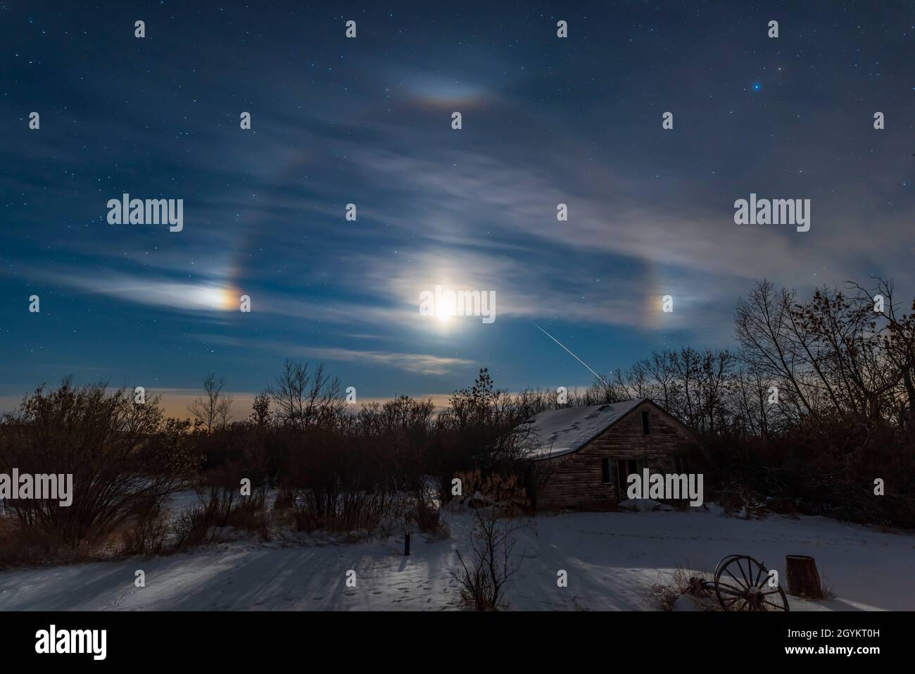 A display of moondogs (technically known as paraselenae) on either side of the waxing crescent Moon with a lunar halo and upper tangent arc, all cause Stock Photo