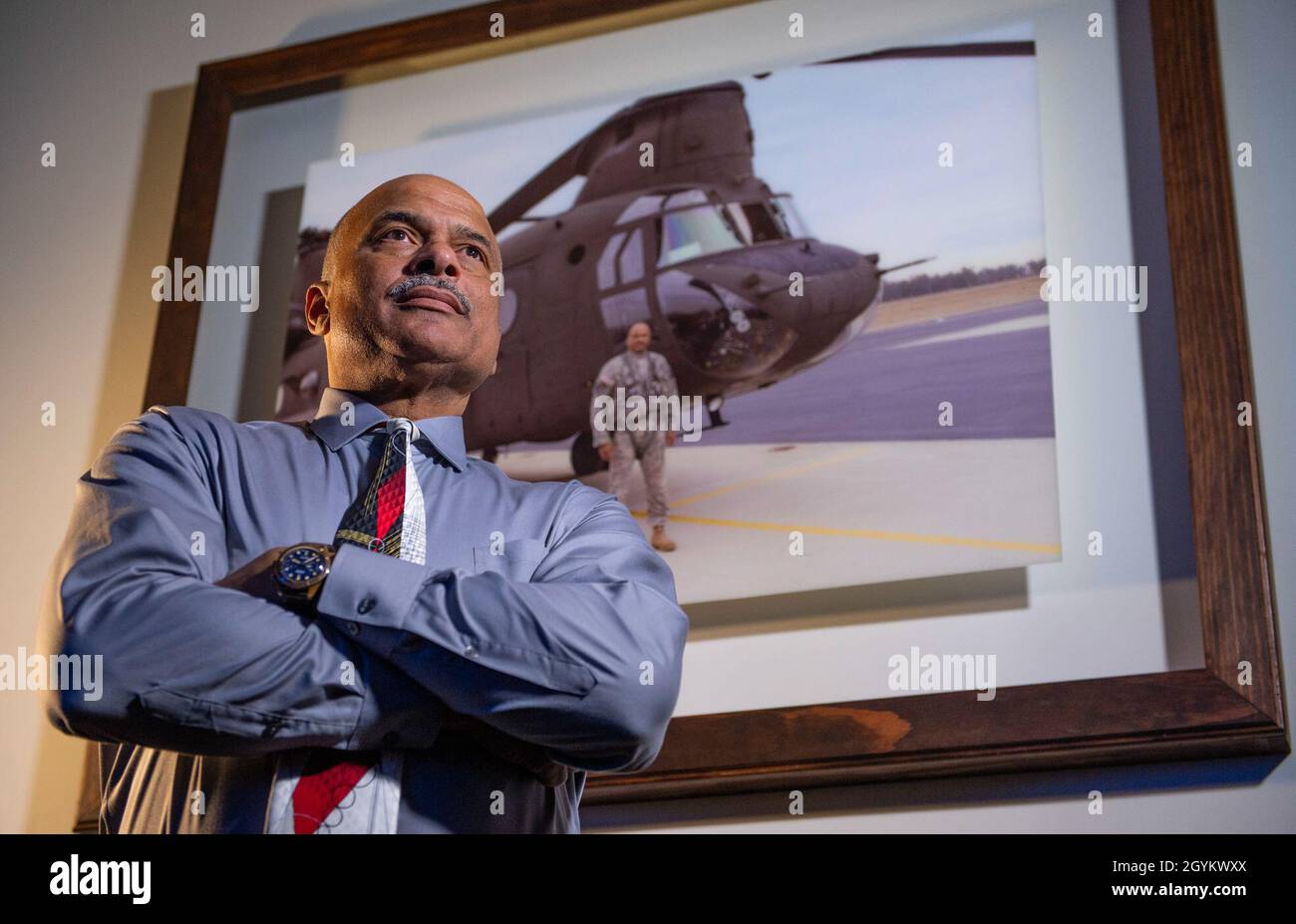 Phillip Brashear, a weapons system manager for the Defense Logistics Agency and a U.S. Army Reserve warrant officer, poses next to a picture of him with a CH-47D Chinook helicopter he flew for the Army, at his job in Richmond, Virginia, Jan. 23, 2020. Phillip Brasher is the son of Carl Brashear, the first African-American master diver in U.S. Navy’s history who lost his leg during a tragic accident on a diver mission off the coast of Spain in 1966. Carl Brashear’s life story about overcoming physical and racial adversity was featured in the Hollywood film “Men of Honor” starring Cuba Gooding J Stock Photo