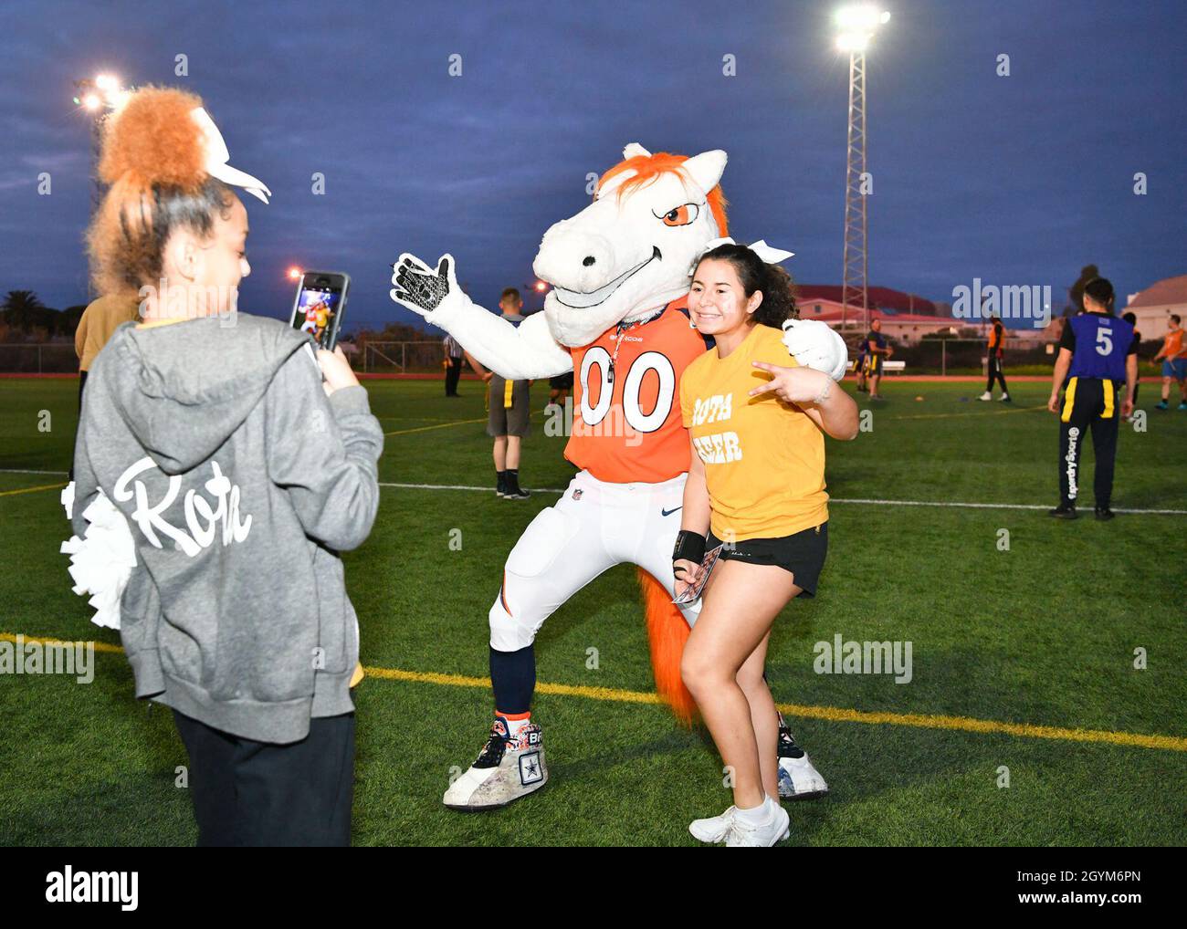 200128-N-KH151-0283 NAVAL STATION ROTA, Spain (Jan. 28, 2020) The Denver Broncos mascot, Miles, poses for a photo with a Rota David Glasgow Farragut (DGF) middle/high school cheerleader during an exhibition flag football game between Sailors and Marines at Naval Station (NAVSTA) Rota. Naval Station Rota sustains the fleet, enables the fighter and supports the family by conducting air operations, port operations, ensuring security and safety, assuring quality of life and providing the core services of power, water, fuel and information technology. (U.S. Navy photo by Mass Communication Speciali Stock Photo