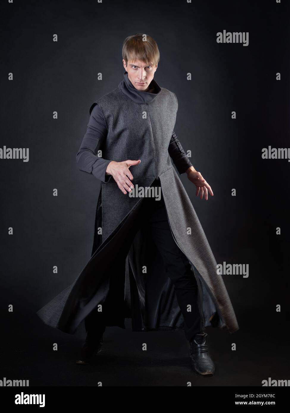 A villain with a red lightsaber, a young man in a long robe does fighting poses, fantasy or science fiction Stock Photo
