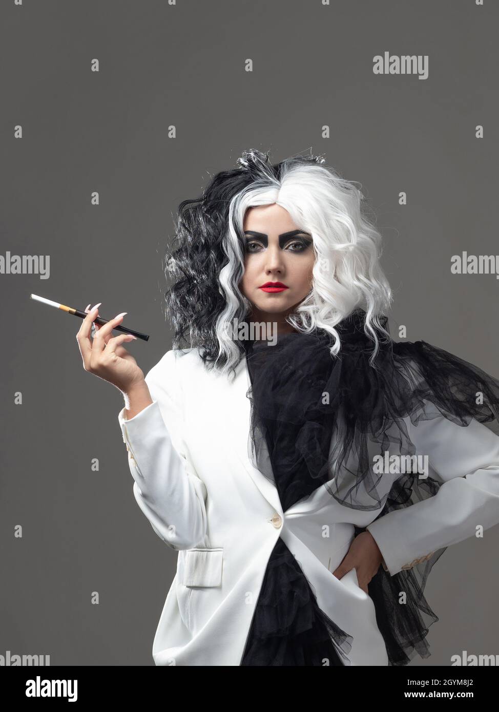 A charismatic unusual woman in a black and white outfit with black and  white hair smokes a cigarette using a mouthpiece, a bold and stylish image  of a Stock Photo