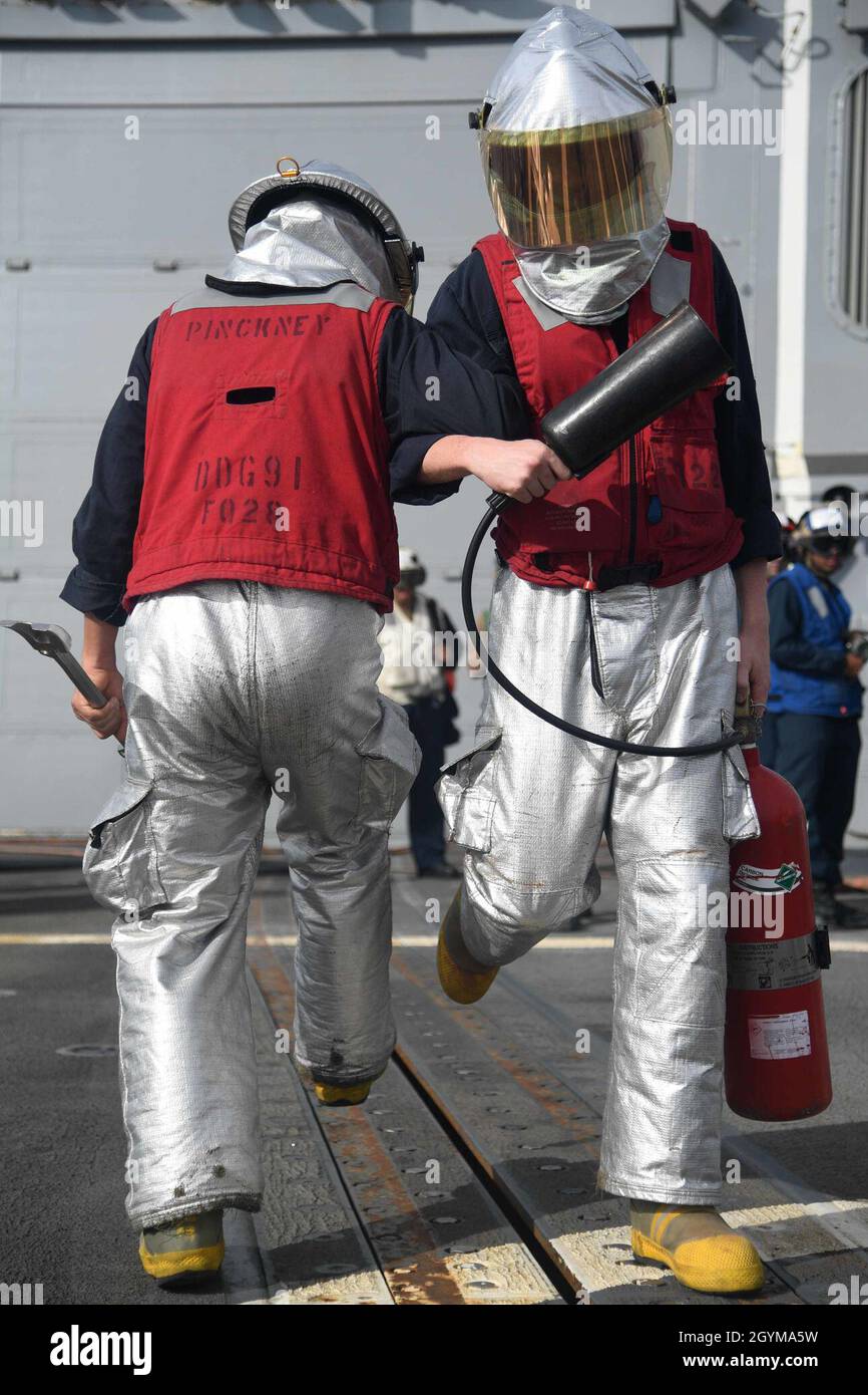 PACIFIC OCEAN (Jan. 29, 2020) Hull Maintenance Technician 2nd Class Caleb Broski, from Texarkana, Ark., right, and Damage Controlman 2nd Class Thomas Lopez, from Dallas, simulate backing away from a helicopter during a crash-and-salvage drill on the flight deck of the Arleigh Burke-class guided-missile destroyer USS Pinckney (DDG 91) Jan. 29, 2020. Pinckney, part of the Theodore Roosevelt Carrier Strike Group, is on a scheduled deployment to the Indo-Pacific. (U.S. Navy photo by Mass Communication Specialist 3rd Class Erick A. Parsons) Stock Photo