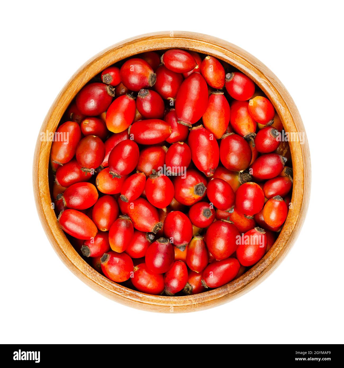 Fresh wild rose hips in a wooden bowl. Also rose haw or rose hep. Ripe and intense red fruits, used for herbal teas, jam and can be eaten raw. Stock Photo