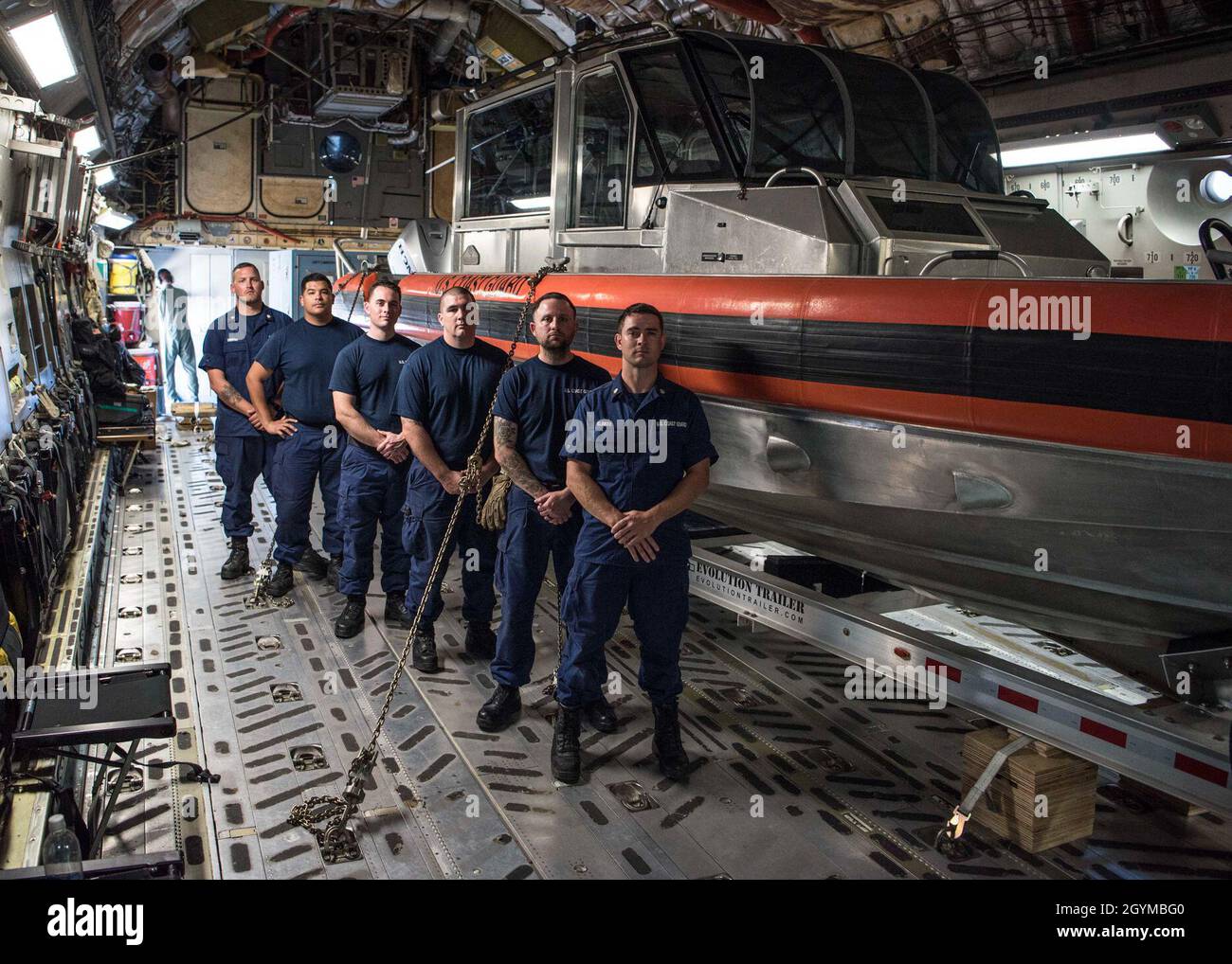 Joint Maritime Safety and Security Teams from the Coast Guard stand next to a USCG vessel they have uploaded to a C-17 Globemaster III aircraft during exercise Patriot Palm, Jan. 30, 2020, at Kalaeloa Airport, Hawaii. A joint-team of several military branches participated with the 315th Contingency Response Flight from Joint Base Charleston in support of exercise Patriot Palm. (U.S. Air Force photo by Tech. Sgt. Della Creech) Stock Photo