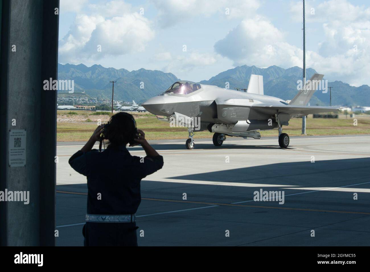 A Hawaii Air National Guard F-22 Raptor crew chief observes an F-35A Lightning II taxi down the flight line Jan. 30, 2020, at Joint Base Pearl Harbor-Hickam, Hawaii. Lightning II aircraft, assigned to Luke Air Force Base, Ariz., temporarily relocated to Hawaii to join other flying squadrons in exercise Pacific Raptor. The exercise is held to integrate the world’s most advanced fifth-generation aircraft, practicing combat scenarios alongside designated ‘aggressor’ aircraft. (U.S. Air Force photo by Senior Airman John Linzmeier) Stock Photo