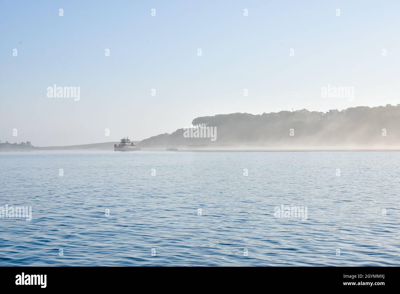 Early summer morning fog scene with tugboat in Port Jefferson Harbor, Long Island, NY. Copy space. Stock Photo