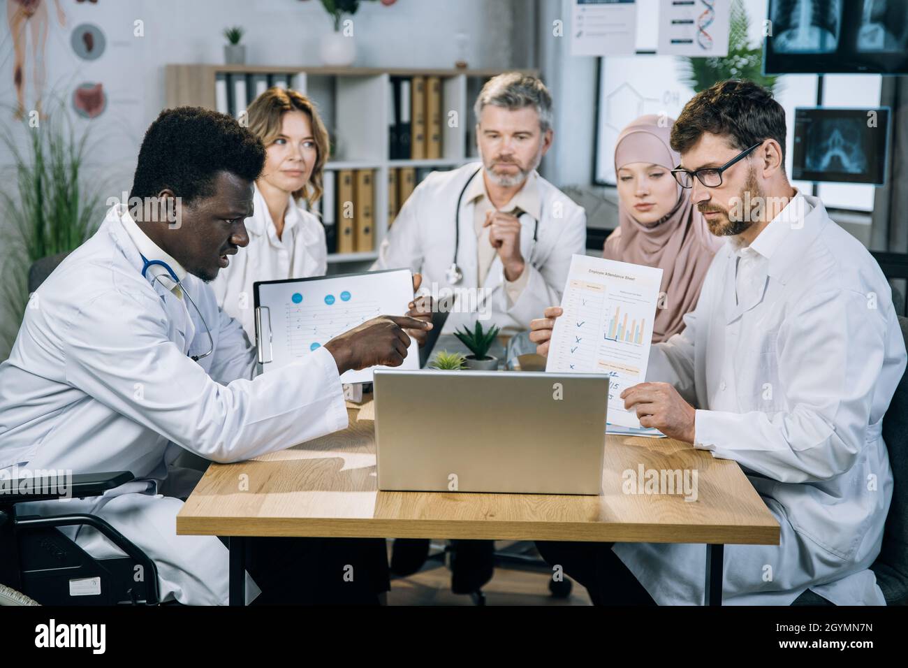 Five multi ethnic medical specialists showing various charts and graphs ...