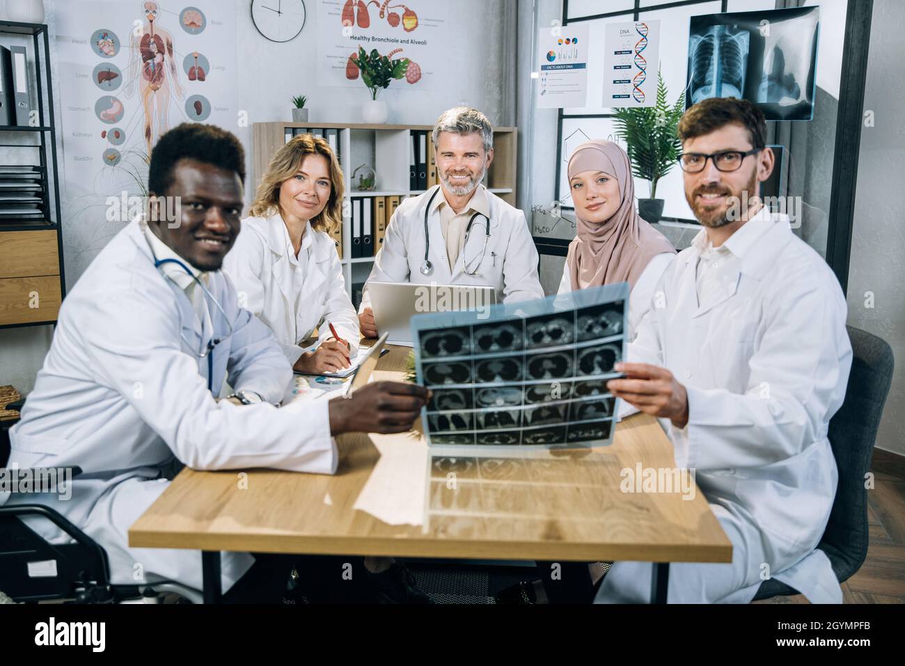 Multicultural doctors with one colleague in wheelchair looking at ...