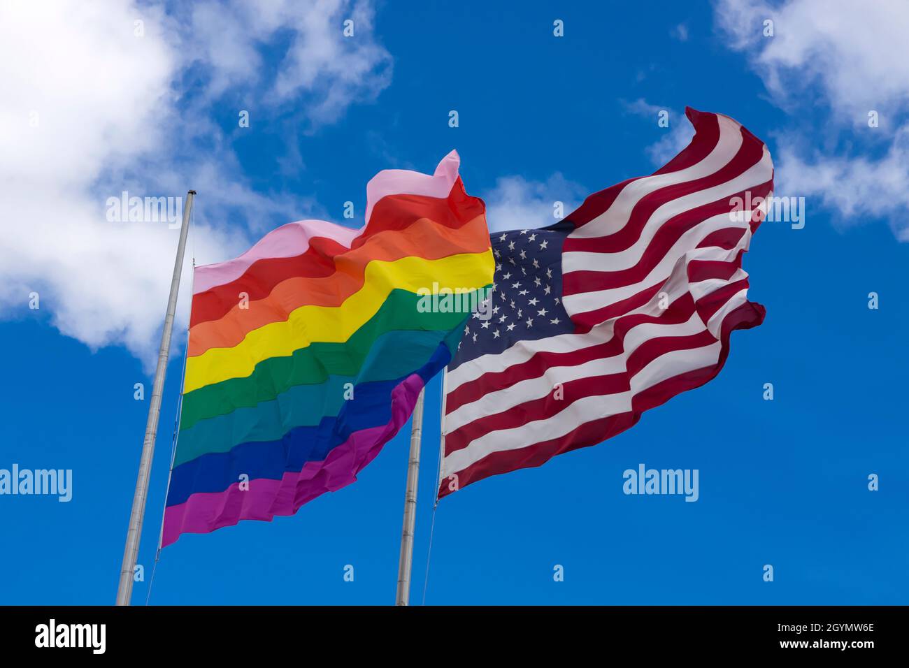 Rainbow flag/gay pride flag (LGBT) flying next to American flag on Cherry Grove, Fire Island, New York, United States of America. Stock Photo