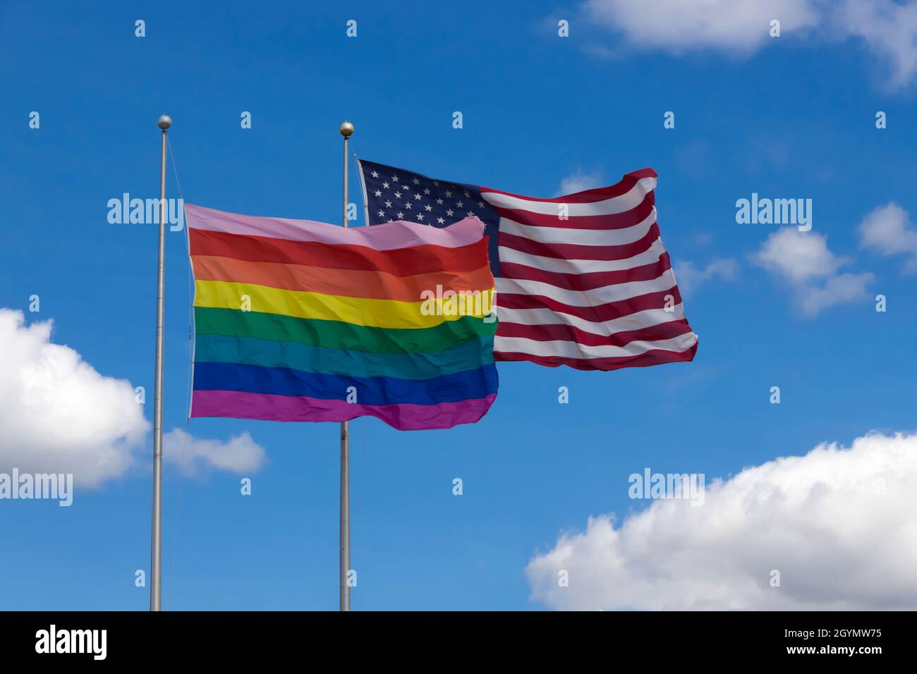 Rainbow flag/gay pride flag (LGBT) flying next to American flag on Cherry Grove, Fire Island, New York, United States of America. Stock Photo