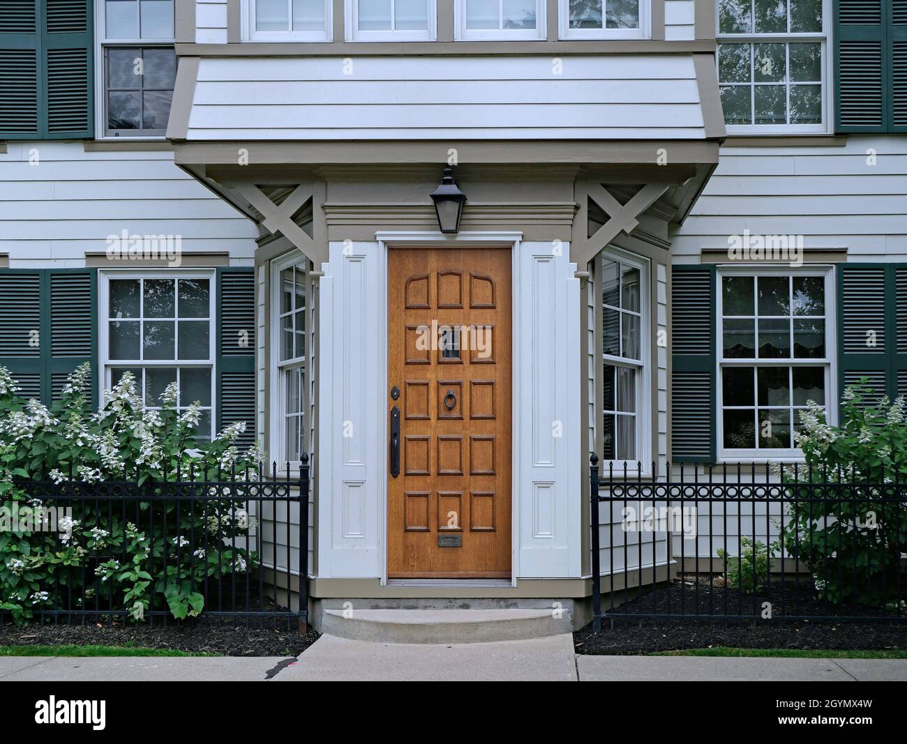 Wood grain front door of old fashioned white clapboard house with shutters Stock Photo
