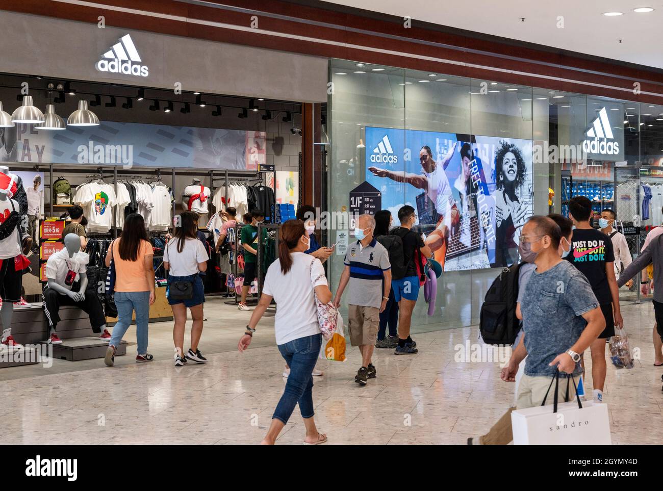 Shoppers walk past the German multinational sportswear brand Adidas store  and logo in Hong Kong Stock Photo - Alamy