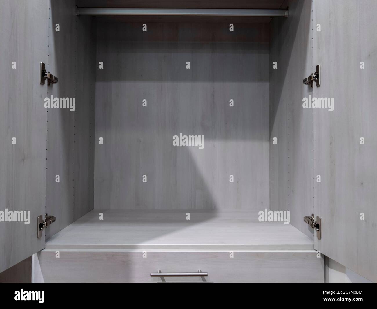 Straight on view of a spacious, empty gray cabinet inside a large walk in closet Stock Photo