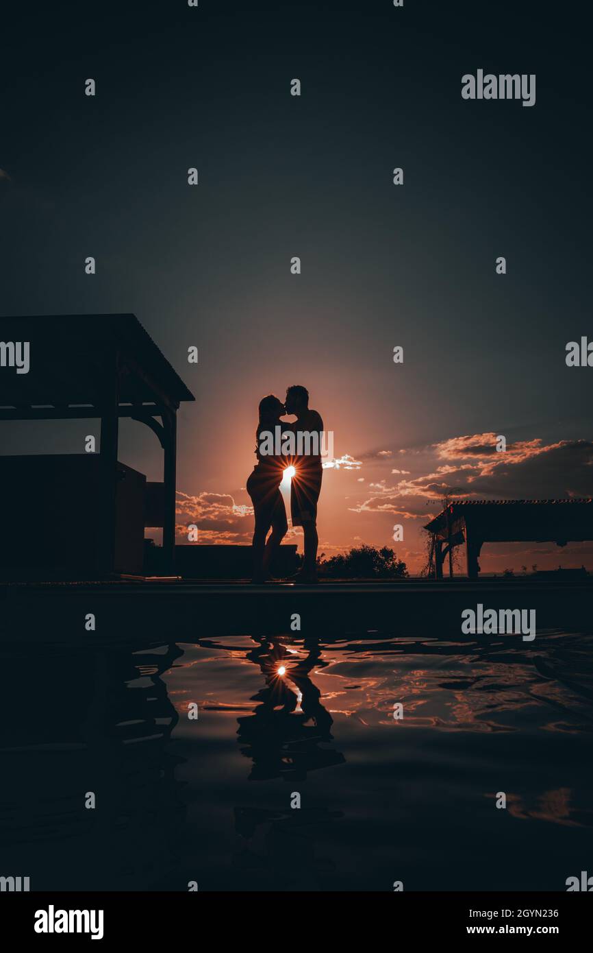 Silhouette of a romantic couple kissing against a sunset sky Stock ...