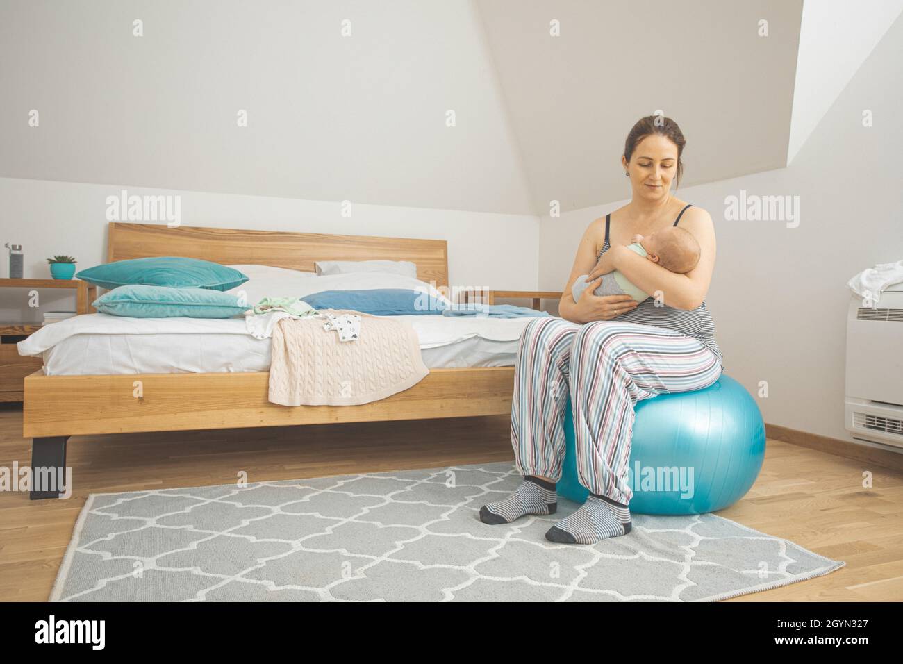 Mother holding and rocking baby sitting on fitball Stock Photo - Alamy