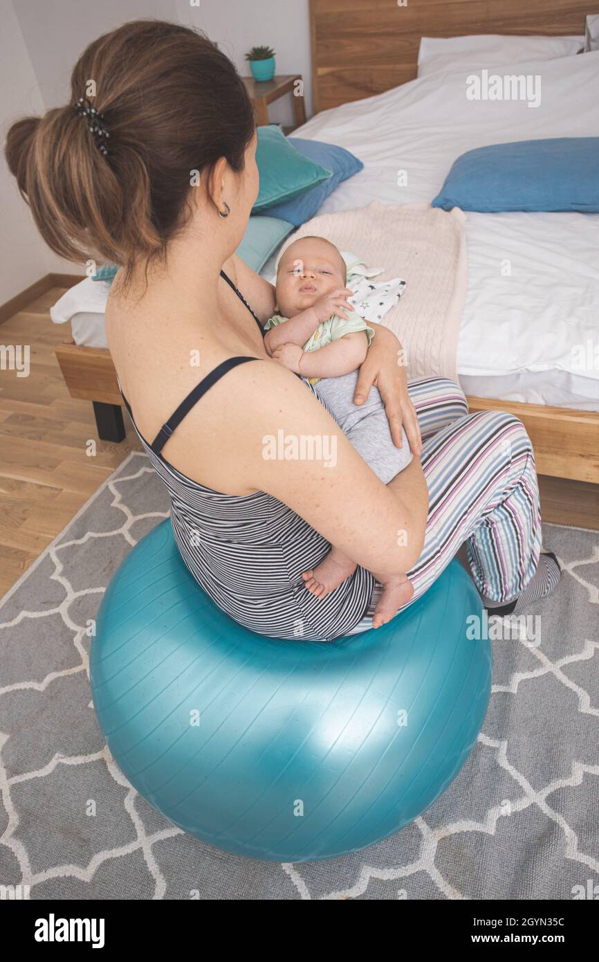 Mother holding and rocking baby sitting on fitball Stock Photo - Alamy