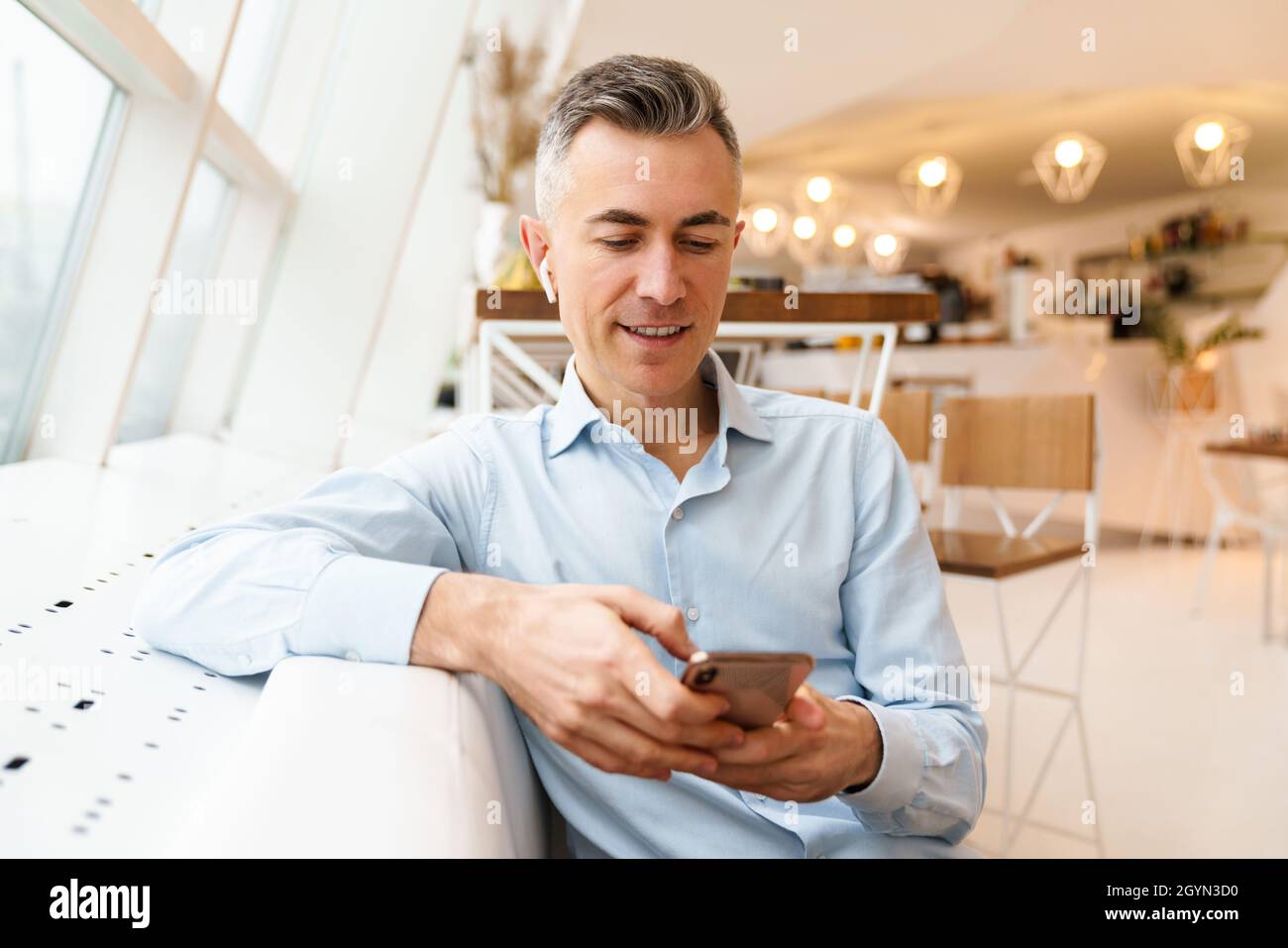 Confident handsome businessman using smartphone in cafe indoors Stock Photo