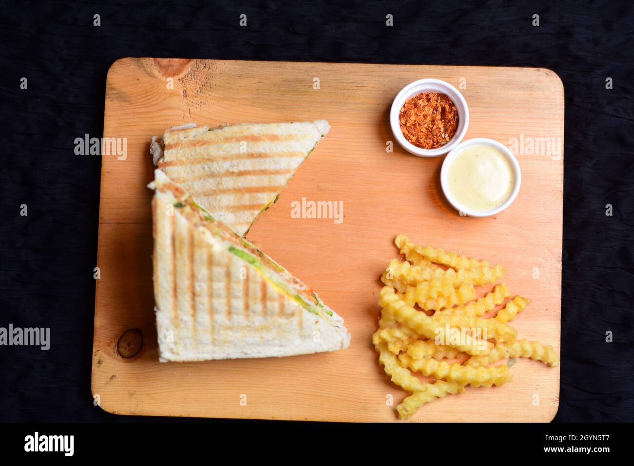 Chicken Sandwich with Curley French Fries On a wood board with black background Stock Photo