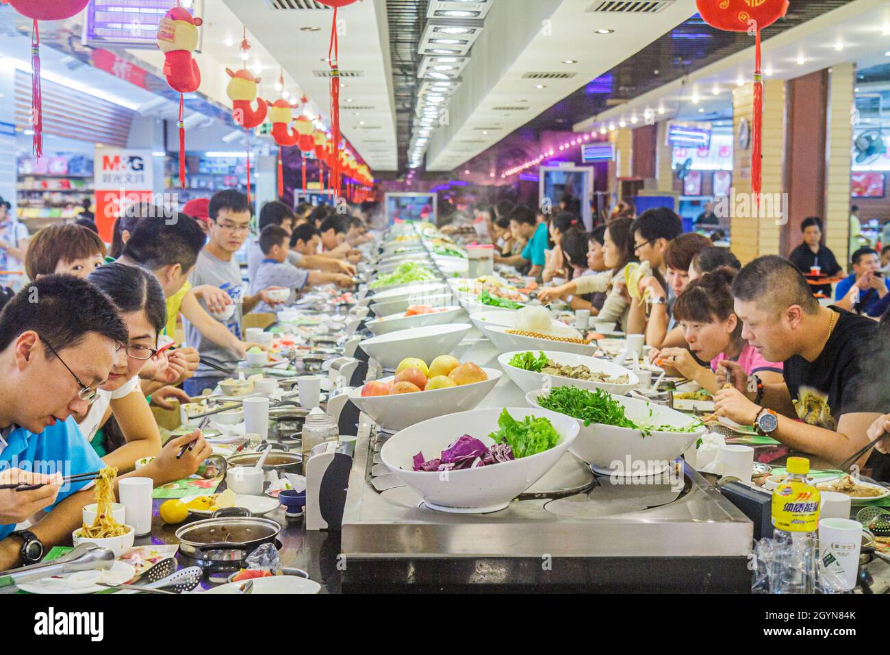 Beijing China,Guanganmen Outer Street,Rainbow Center Asian man male woman female couple,eating restaurant dining food conveyor belt Kaiten-zushi sushi Stock Photo