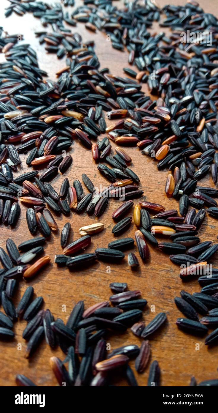 Vertical closeup shot of black rice seeds on a wooden table Stock Photo ...