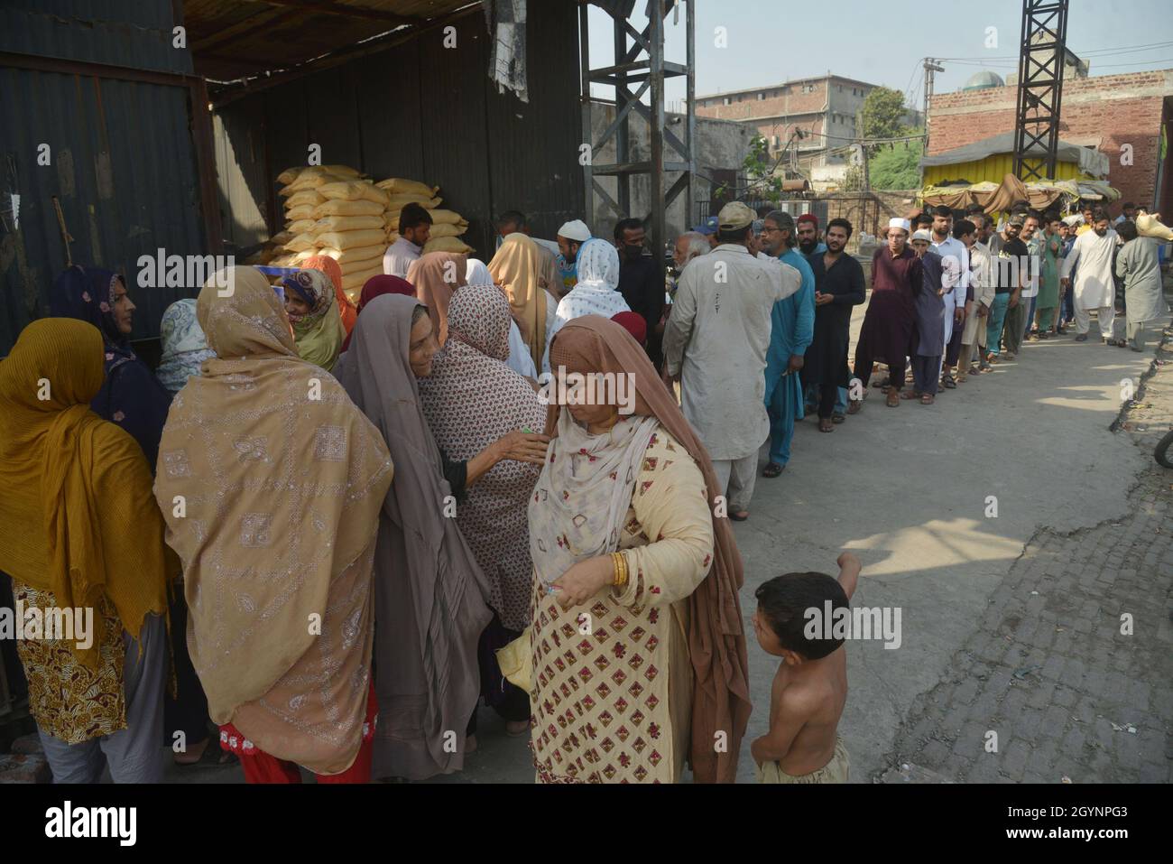 Lahore, Pakistan. 08th Oct, 2021. A large numbers of Pakistani people stand in queue for the essential commodity in buying flour bags on subsidies price in Lahore. Punjab government selling flour with fix 20 kg sack Rs-1080 and 10kg sack Rs-540 at Band road area in Lahore. Wheat flour has emerged as one of the most sought-after essential items after rice, pulses, sugar, ghee/cooking oil, tea, milk, etc. (Photo by Rana Sajid Hussain/Pacific Press) Credit: Pacific Press Media Production Corp./Alamy Live News Stock Photo