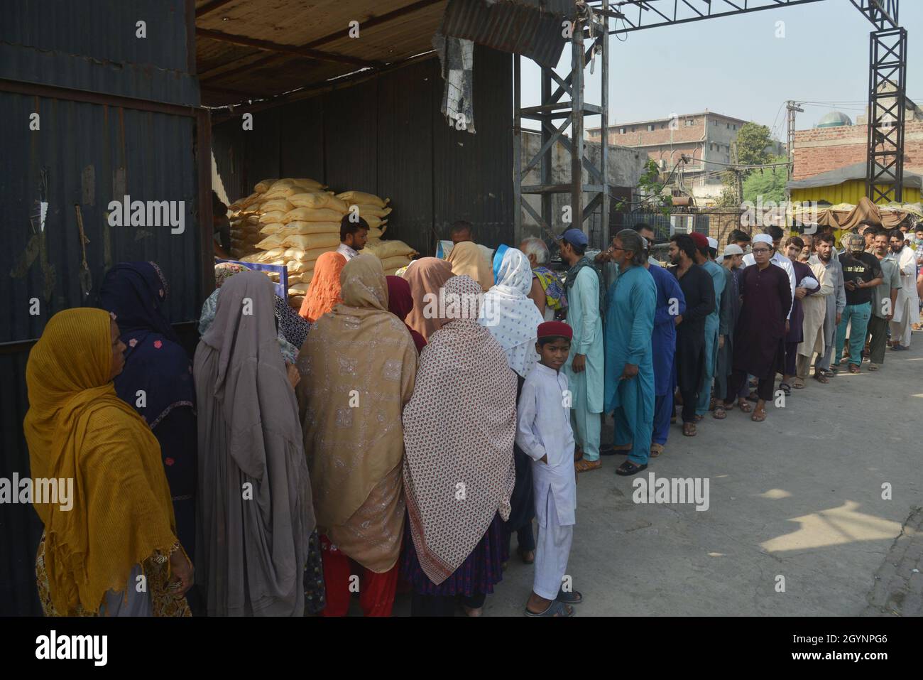 Lahore, Pakistan. 08th Oct, 2021. A large numbers of Pakistani people stand in queue for the essential commodity in buying flour bags on subsidies price in Lahore. Punjab government selling flour with fix 20 kg sack Rs-1080 and 10kg sack Rs-540 at Band road area in Lahore. Wheat flour has emerged as one of the most sought-after essential items after rice, pulses, sugar, ghee/cooking oil, tea, milk, etc. (Photo by Rana Sajid Hussain/Pacific Press) Credit: Pacific Press Media Production Corp./Alamy Live News Stock Photo