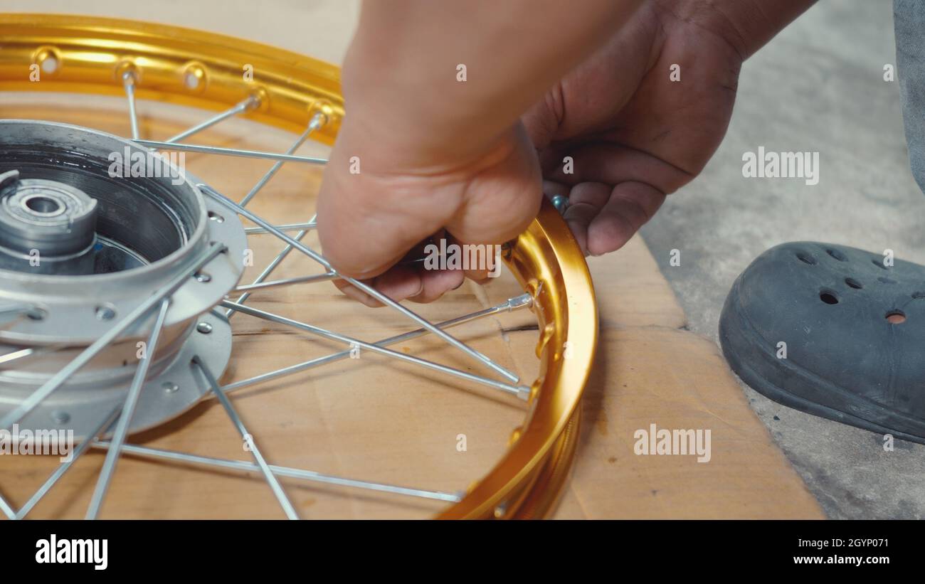 Technician man working motorcycle wheel has spokes weave up on mechanic