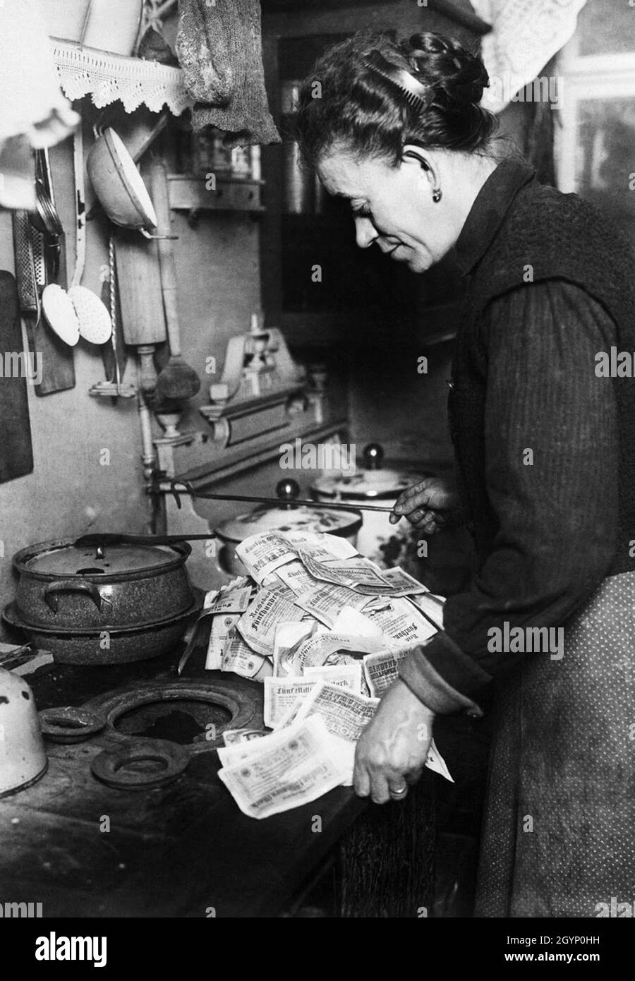 A housewife in Germany in the hyperinflation period using worthless money to start her fire. Stock Photo