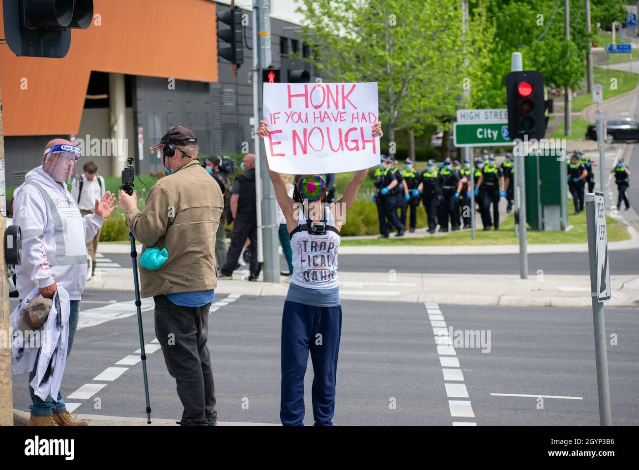 Melbourne, Australia, 9th October 2021. 'Honk if You Have Had Enough'. An anti-lockdown protester holds a sign while another is interviewed, with police officers about to intervene, as part of a roadside rally on Springvale Road. Credit: Jay Kogler/Alamy Live News Stock Photo