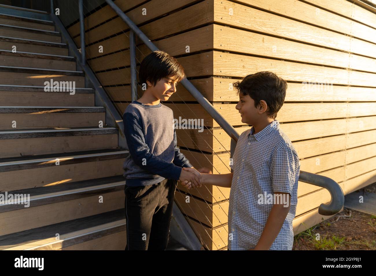 Friends shaking hands. Friendship concept. Two young smiling boys meeting. South Asian kids bonding. Children doing handshake. Stock Photo