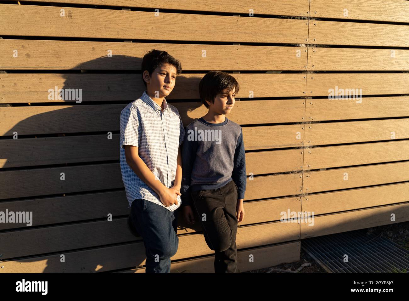 Two South Asian kids standing against wooden wall. Concept of children thinking about future. Friendship concept. Stock Photo