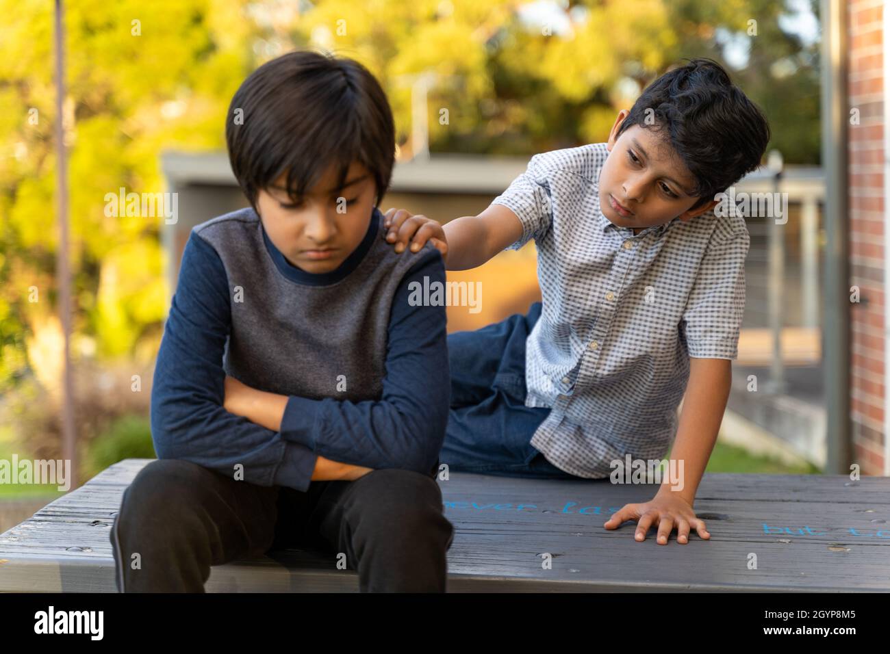 Angry child care. Caring Friendship concept. Giving help concept. Kid giving Support. Golden hour scene of upset child. Hand on shoulder. Stock Photo
