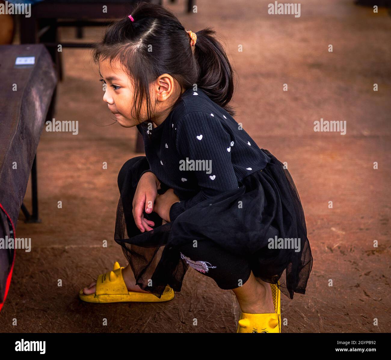 A Little Girl Wearing Black Squats And Plays At A Cafe In Hoi An Stock a-little-girl-wearing-black-squats-and-plays-at-a-cafe-in-hoi-an-stock