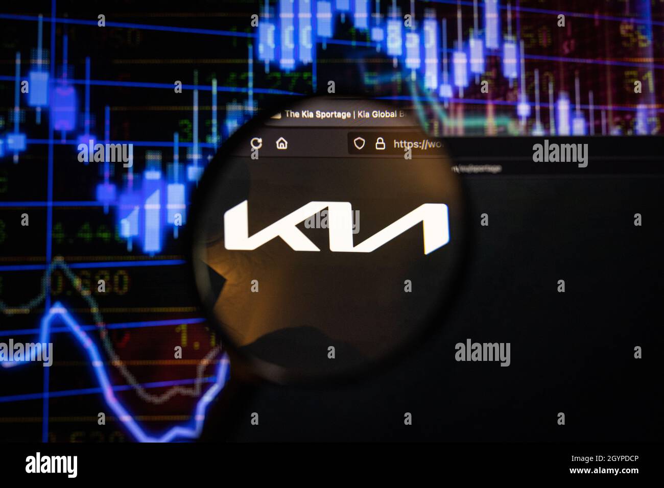 Kia company logo on a website with blurry stock market developments in the background, seen on a computer screen through a magnifying glass Stock Photo