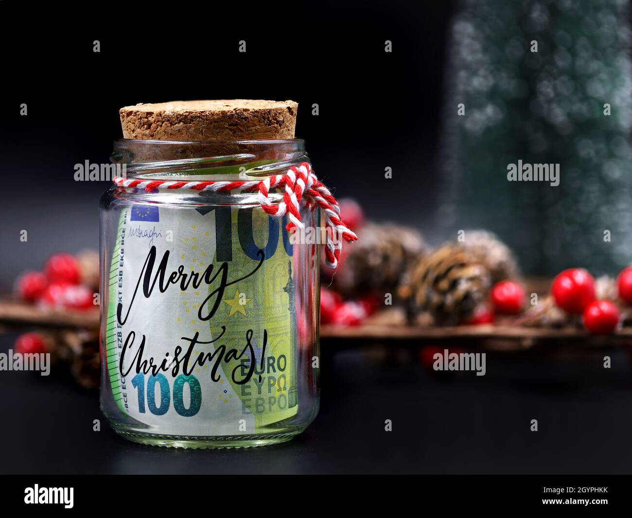 Euro money banknote in christmas jar with text merry christmas on black background with christmas decoration Stock Photo