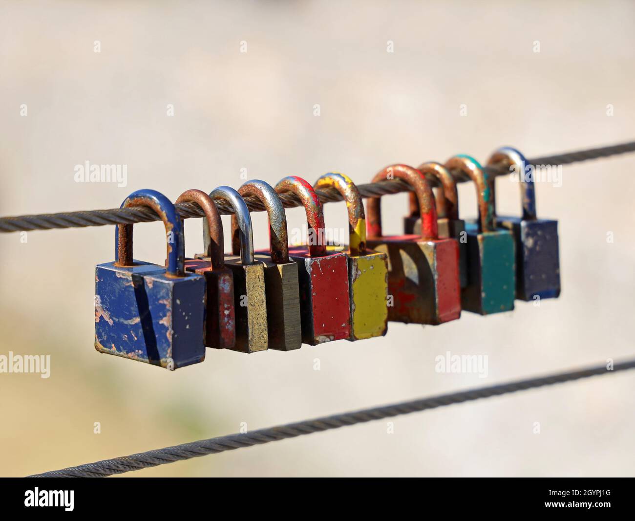rusty old colourful padlocks on steel wire Stock Photo
