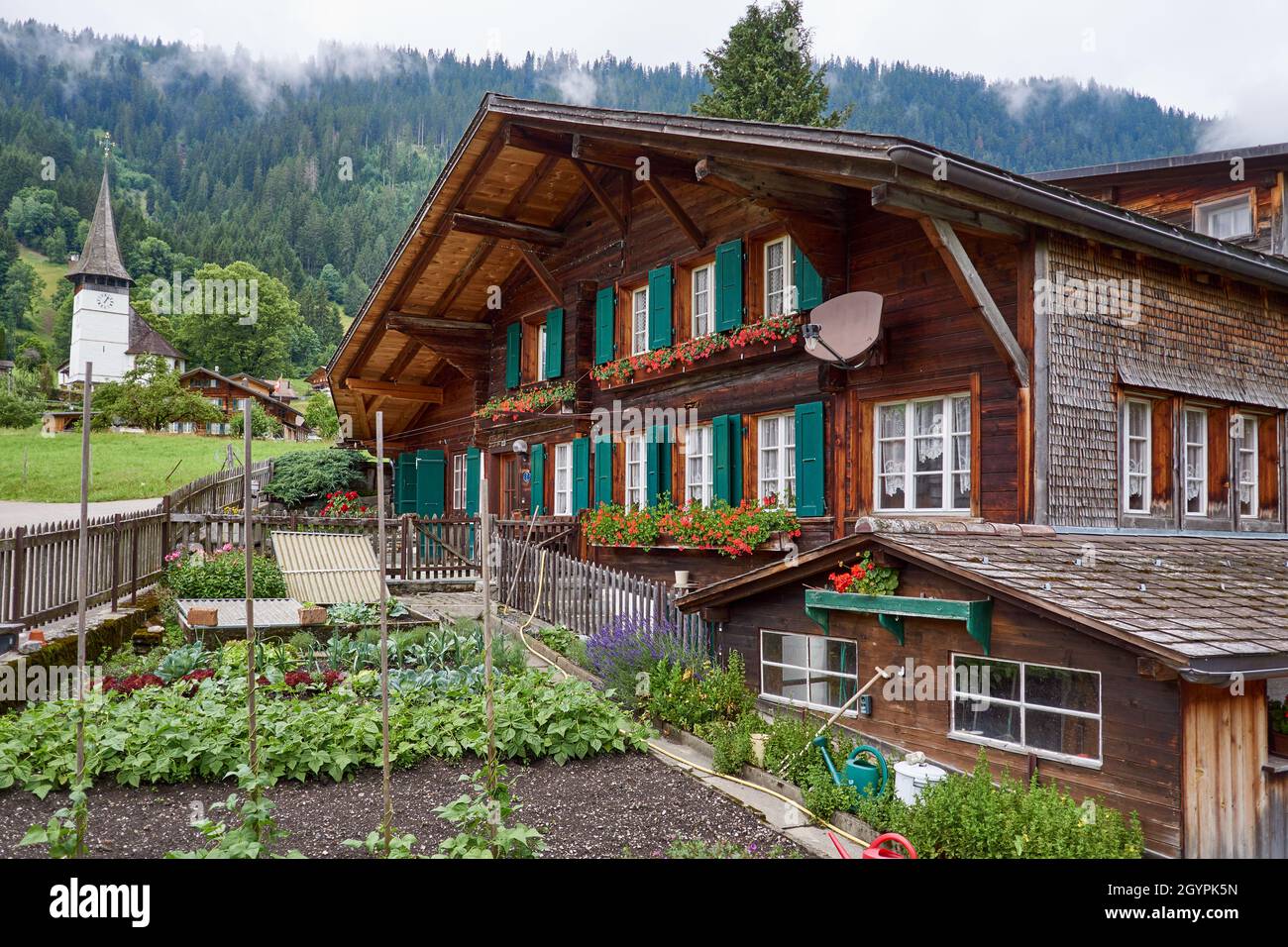 Swiss chalet with garden and church - Simmental, Berner Oberland, Switzerland Stock Photo