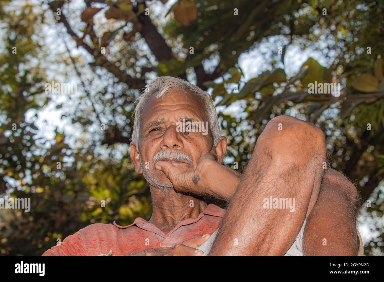 Close-up portrait of Senior citizen Indian man sitting on a chair in the evening sad thinking something, india Stock Photo