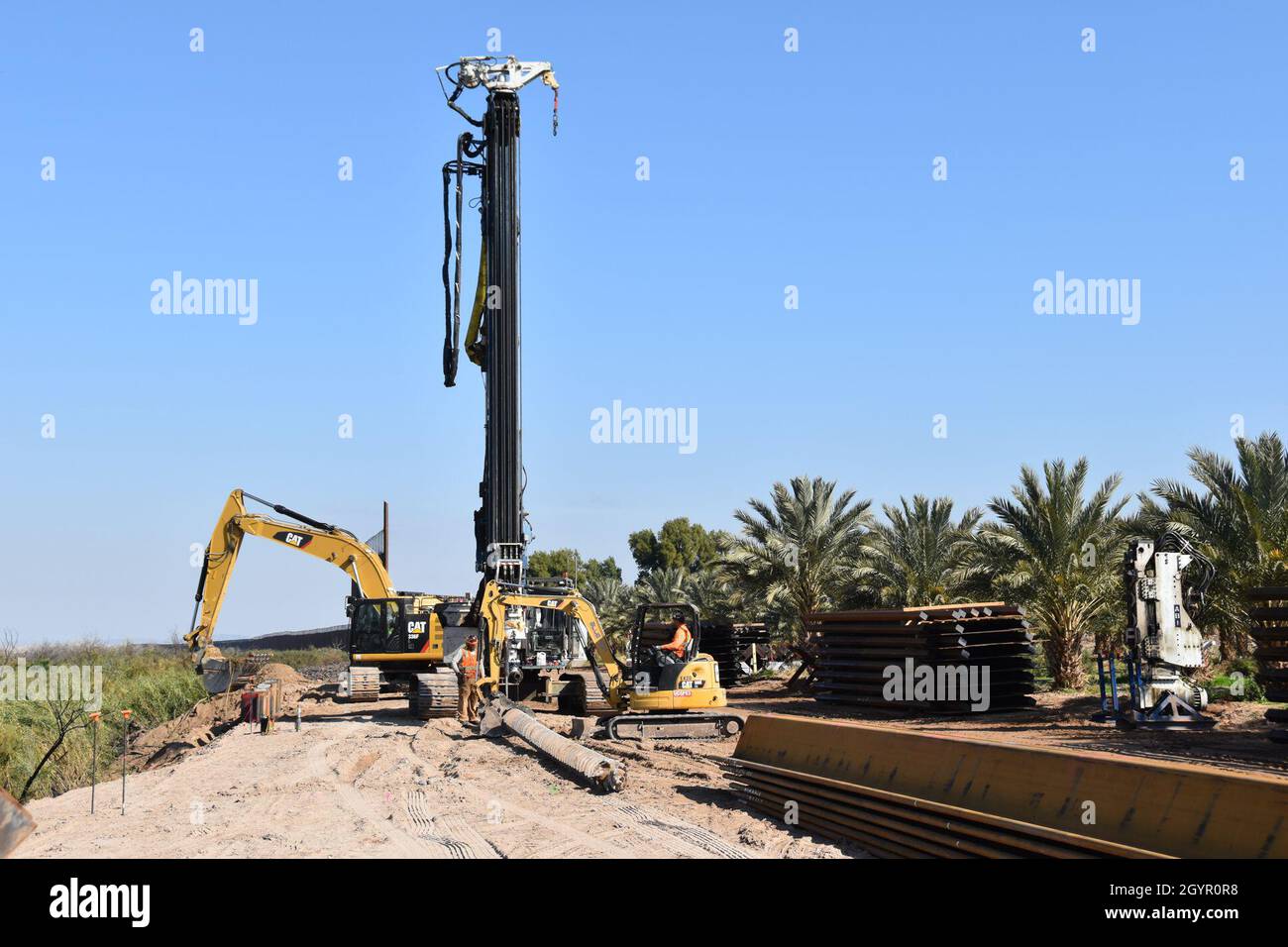 An excavator removes soil and boulders to make way for additional sheet ...